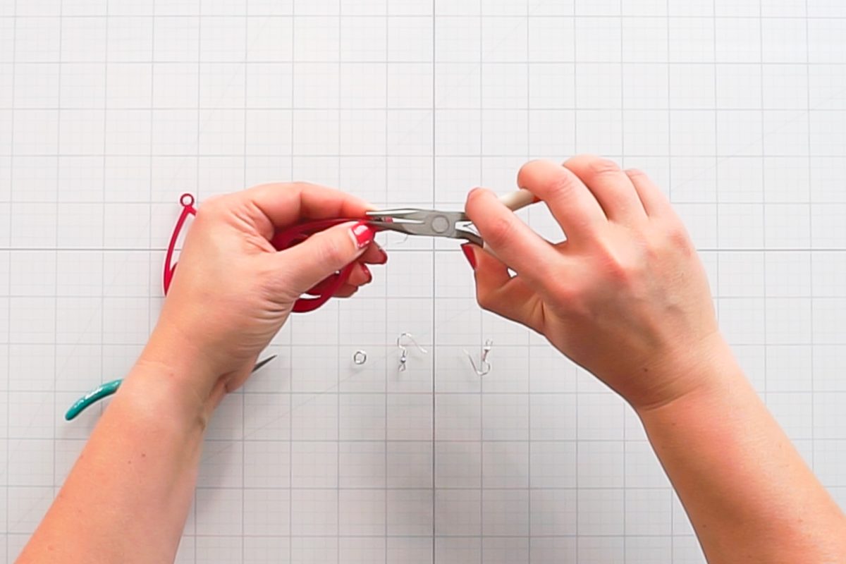 Hands using pliers to attach earring findings.