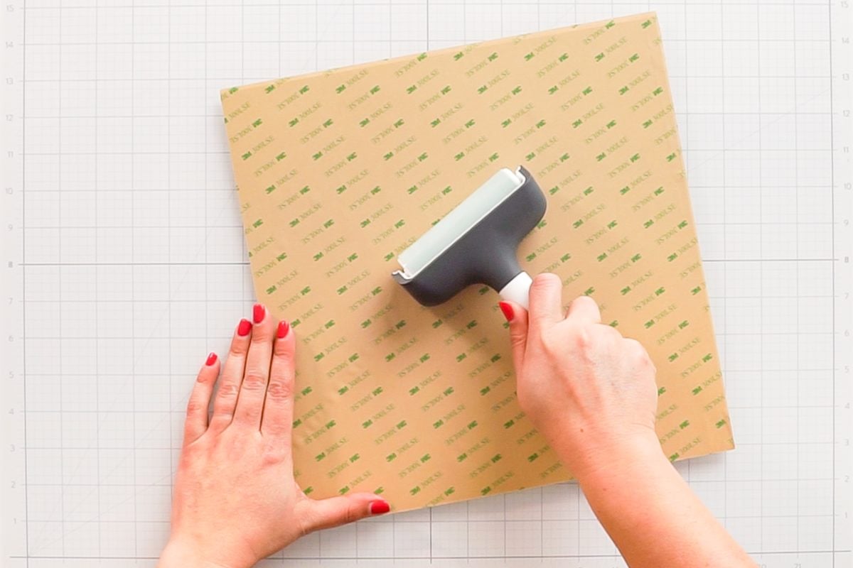 Hands using a brayer to apply the 3M Adhesive