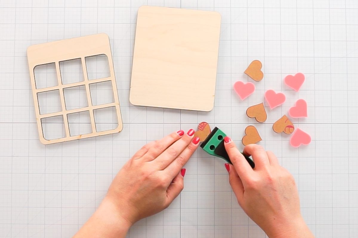 Hands using plastic razor blade to remove masking