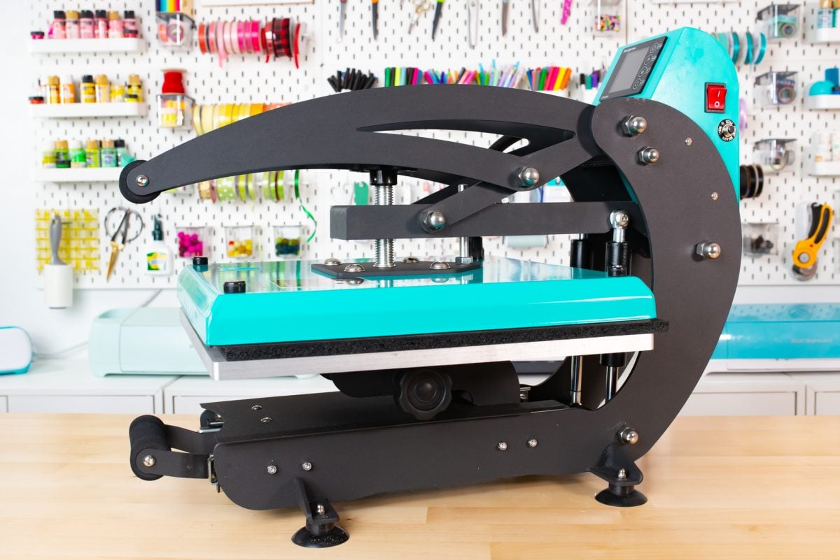 Teal WALApress sitting on workbench with crafty pegboard behind.