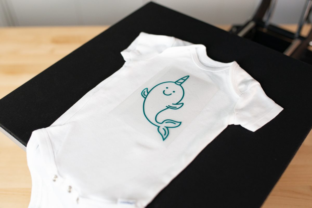 Onesie on platen with the narwhal decal on top.