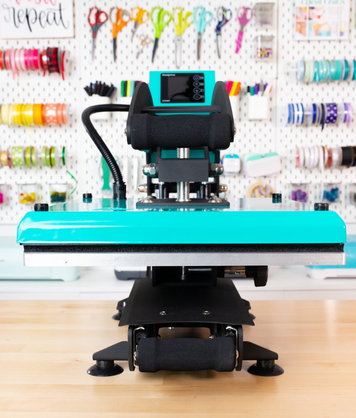 Teal WALApress facing forward on workbench with crafty pegboard behind. 