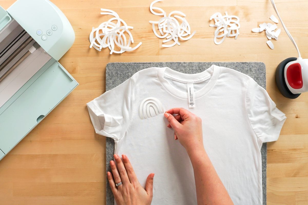 Overhead shot of hand placing rainbow pieces on a white shirt