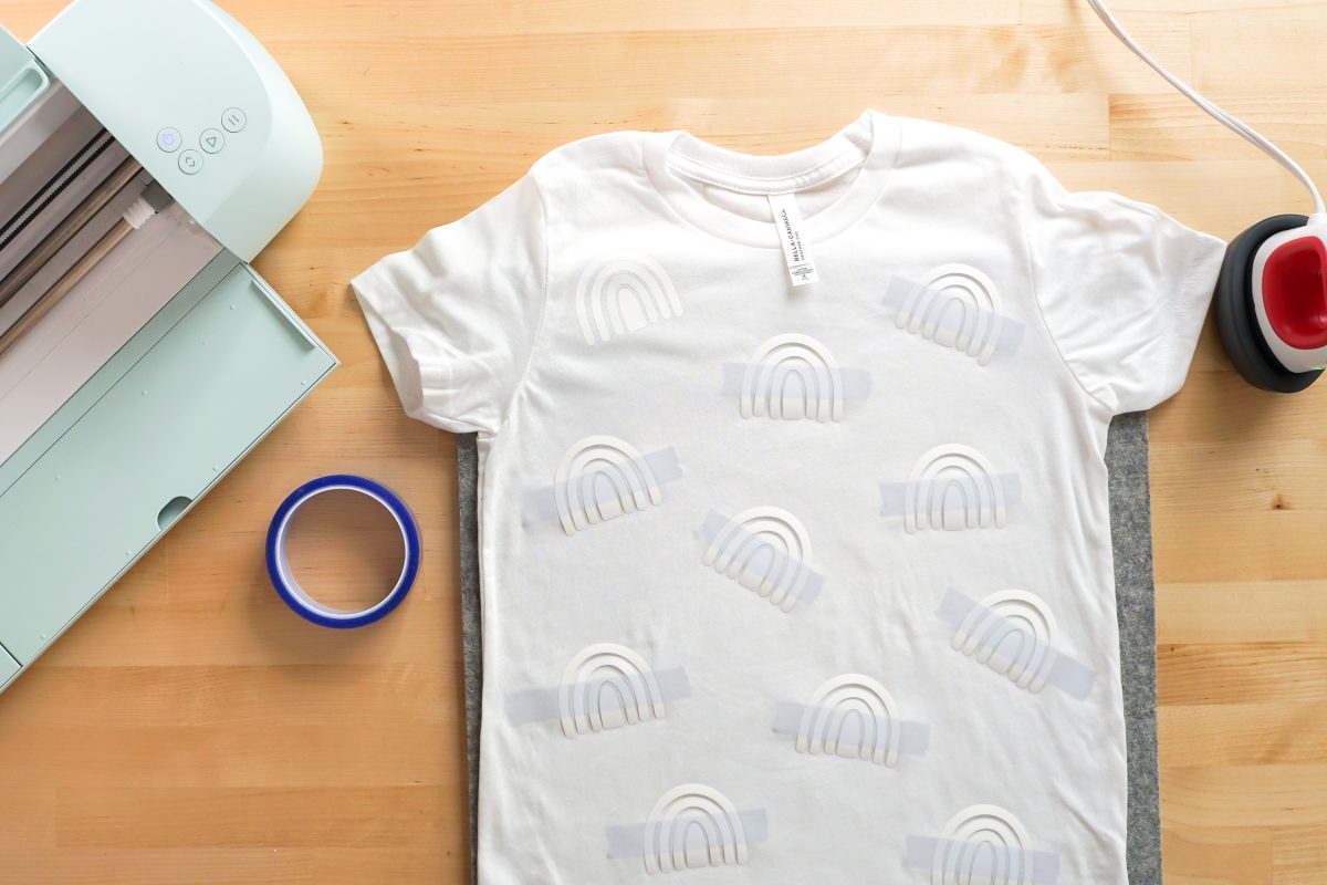 Overhead shot of white shirt with a bunch of rainbows taped and read to be pressed.