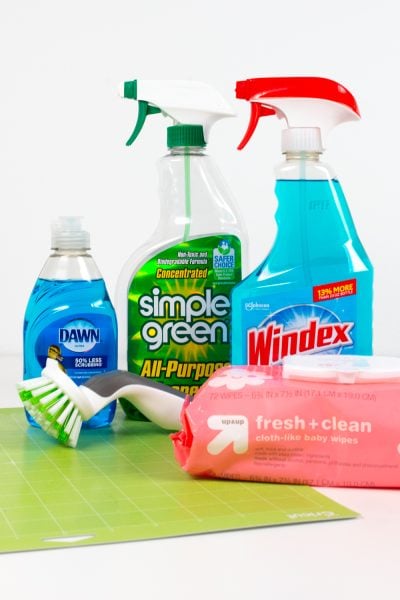 Windex, Simple Green, Dawn, baby wipes, a scrubber brush, and a green Cricut mat.