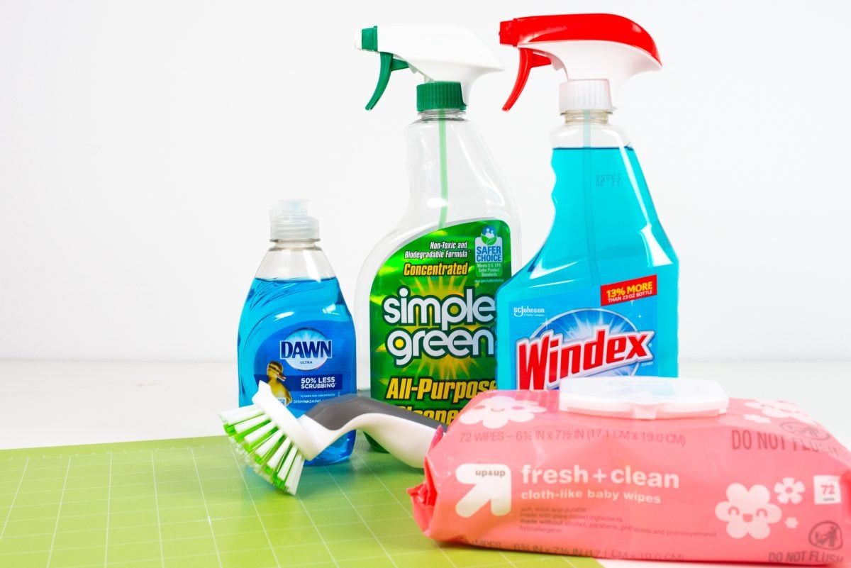 Windex, Simple Green, Dawn, baby wipes, a scrubber brush, and a green Cricut mat.
