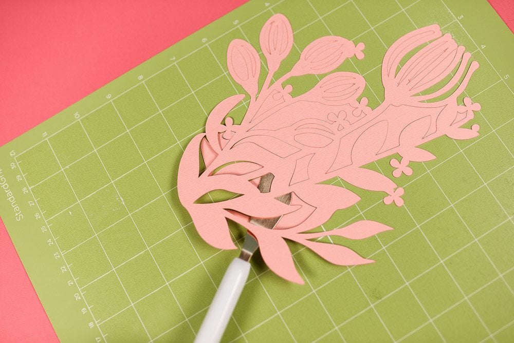 Intricate cardstock project on green cutting mat.