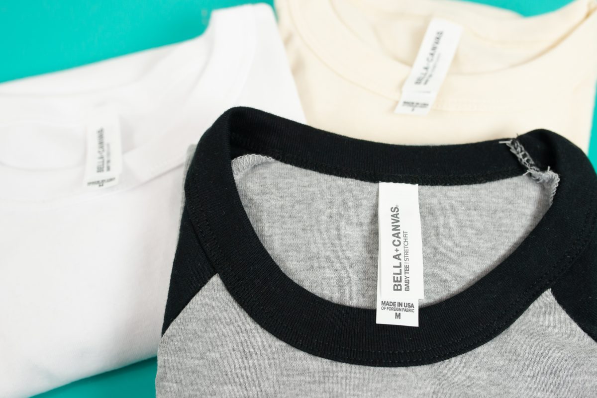 Close-up of three folded BELLA+CANVAS baby tees.