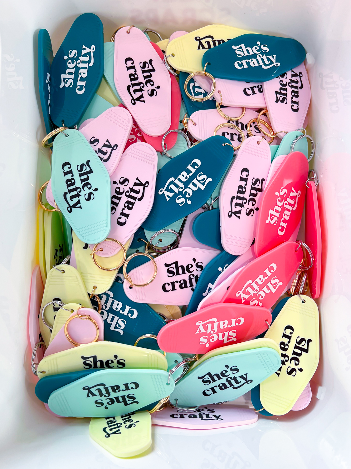 Box of colorful hotel keychains that say "she's crafty" in vinyl