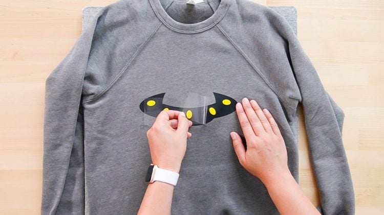 Hands removing carrier sheet from shirt design