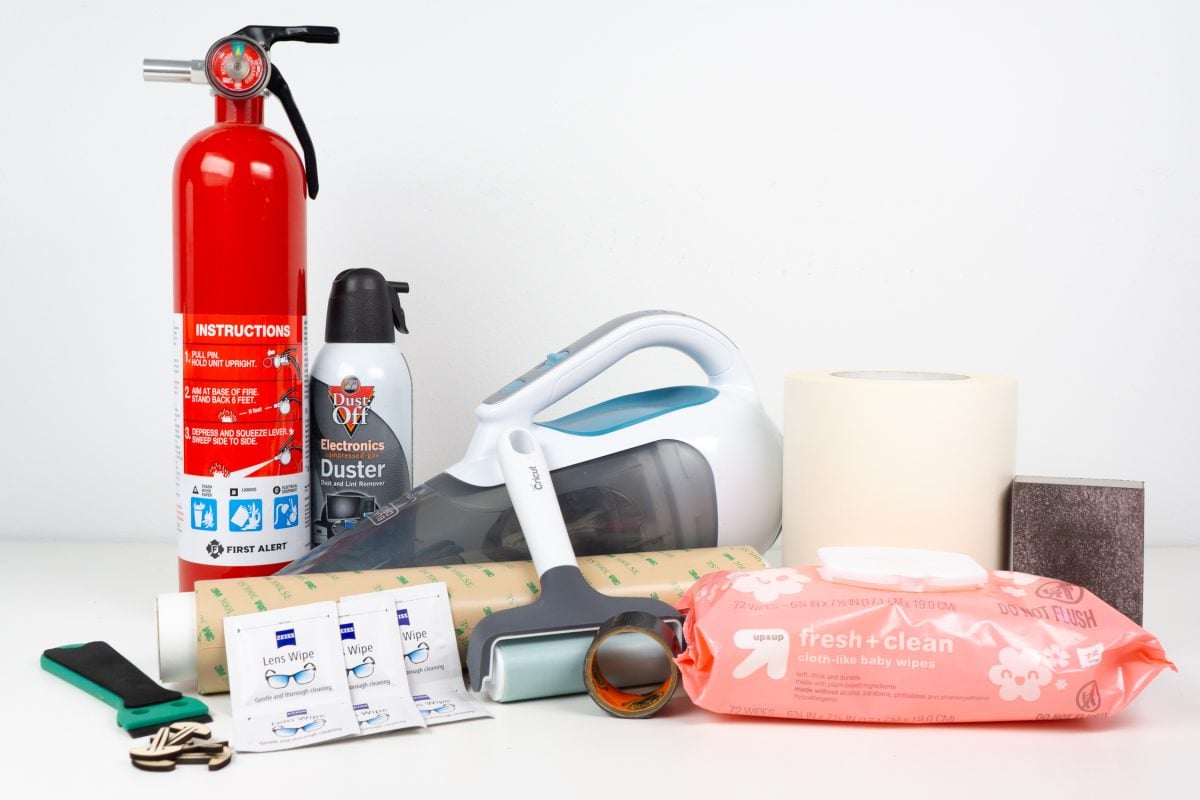 A bunch of laser supplies including a fire extinguisher, vacuum, canned air, masking, brayer, sanding block, bed pins, wipes, Gorilla tape, and plastic razor blade