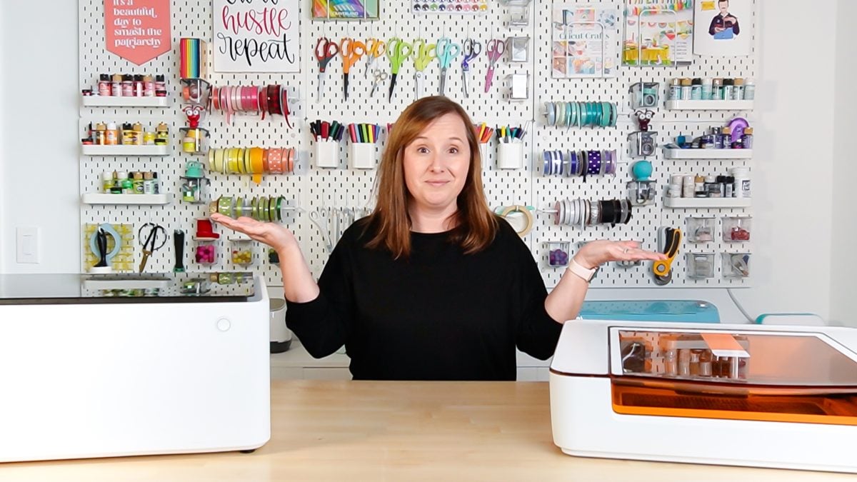 Cori standing next to  the Glowforge Aura and the xTool M1 machines