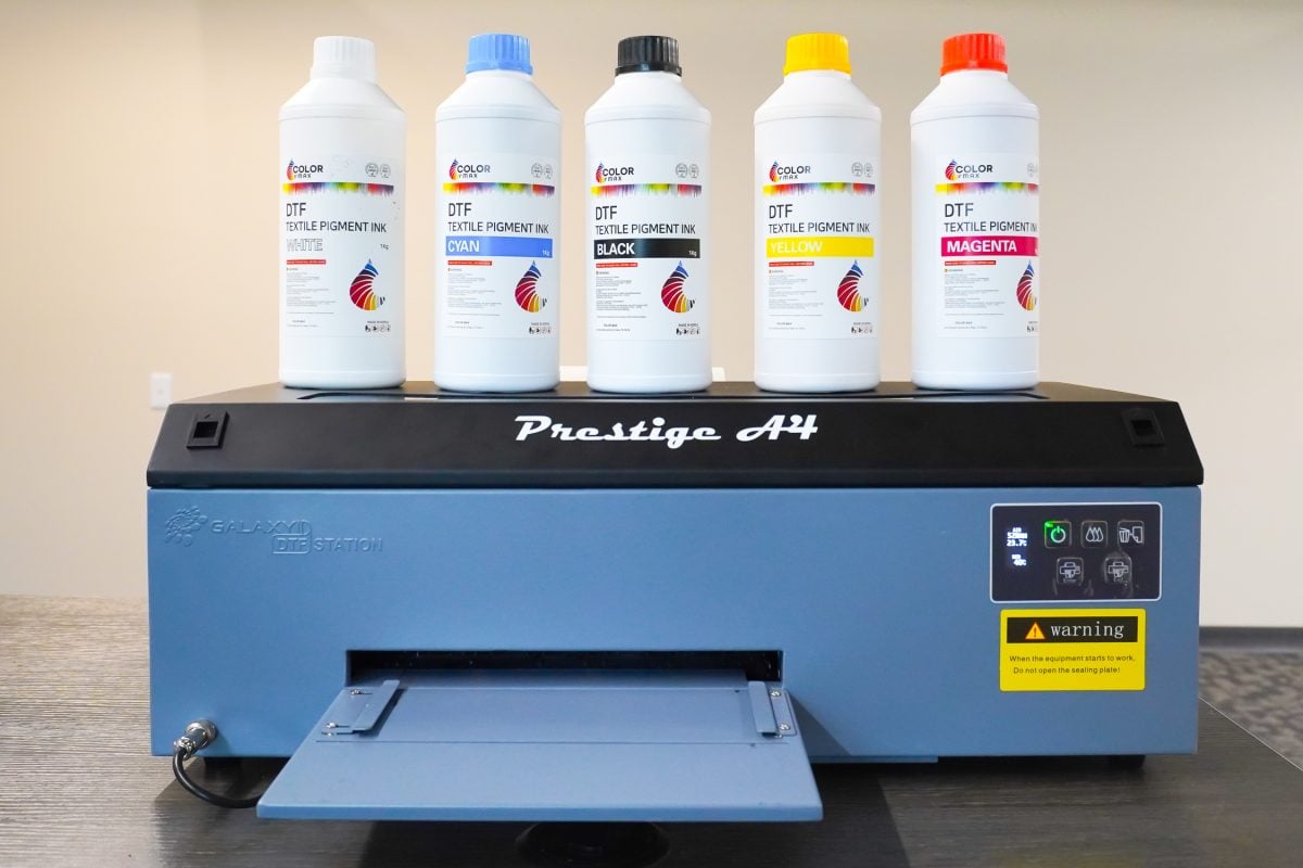 Prestige A4 blue DTF printer with DTF ink bottles on top