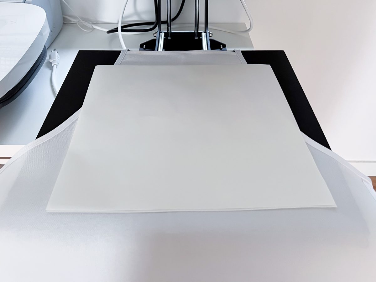 Open heat press with two pieces of butcher paper on top of the apron.