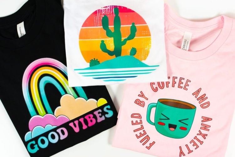 Three shirts with colorful DTF prints on table