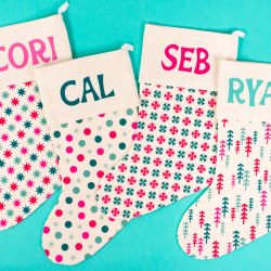 Four patterned Christmas stockings on teal background