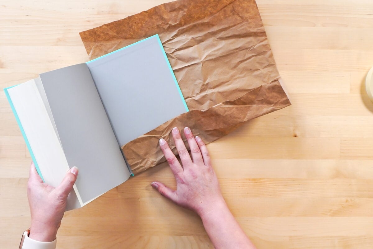 Hands wrapping the book in brown paper