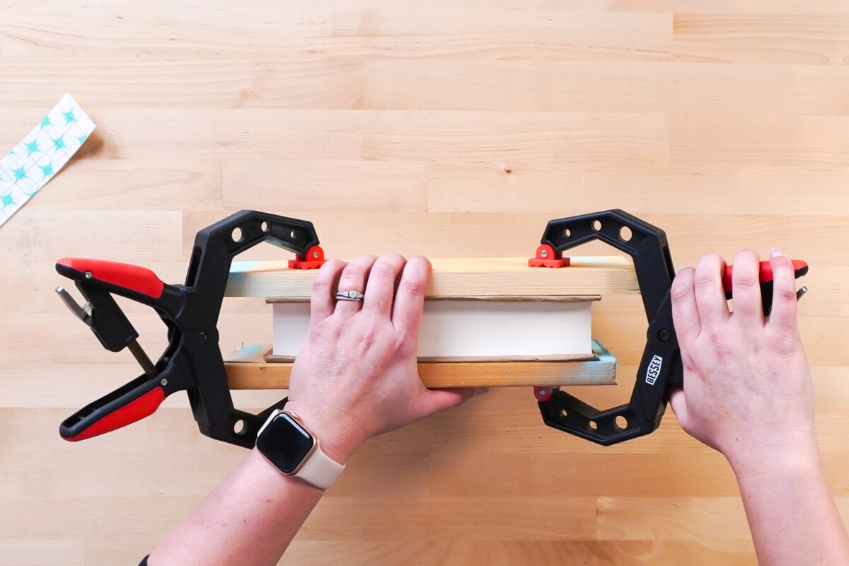 Hands using clamps to clamp book pages together. 