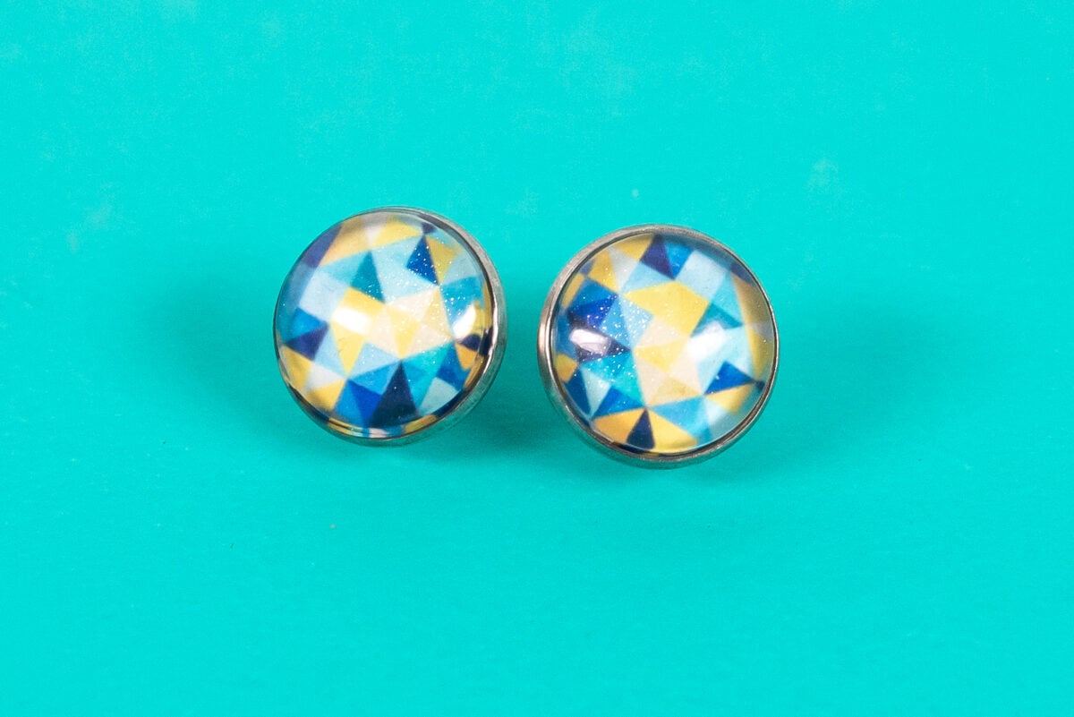 Final stud earrings on a teal background