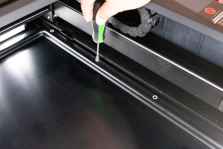Hand using screwdriver to remove screws from the xTool Laser Screen Printer