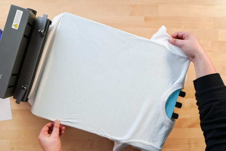 hands adjusting white t-shirt on a heating press
