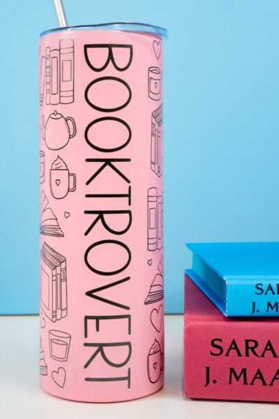 "Booktrovert" tumbler with a stack of books