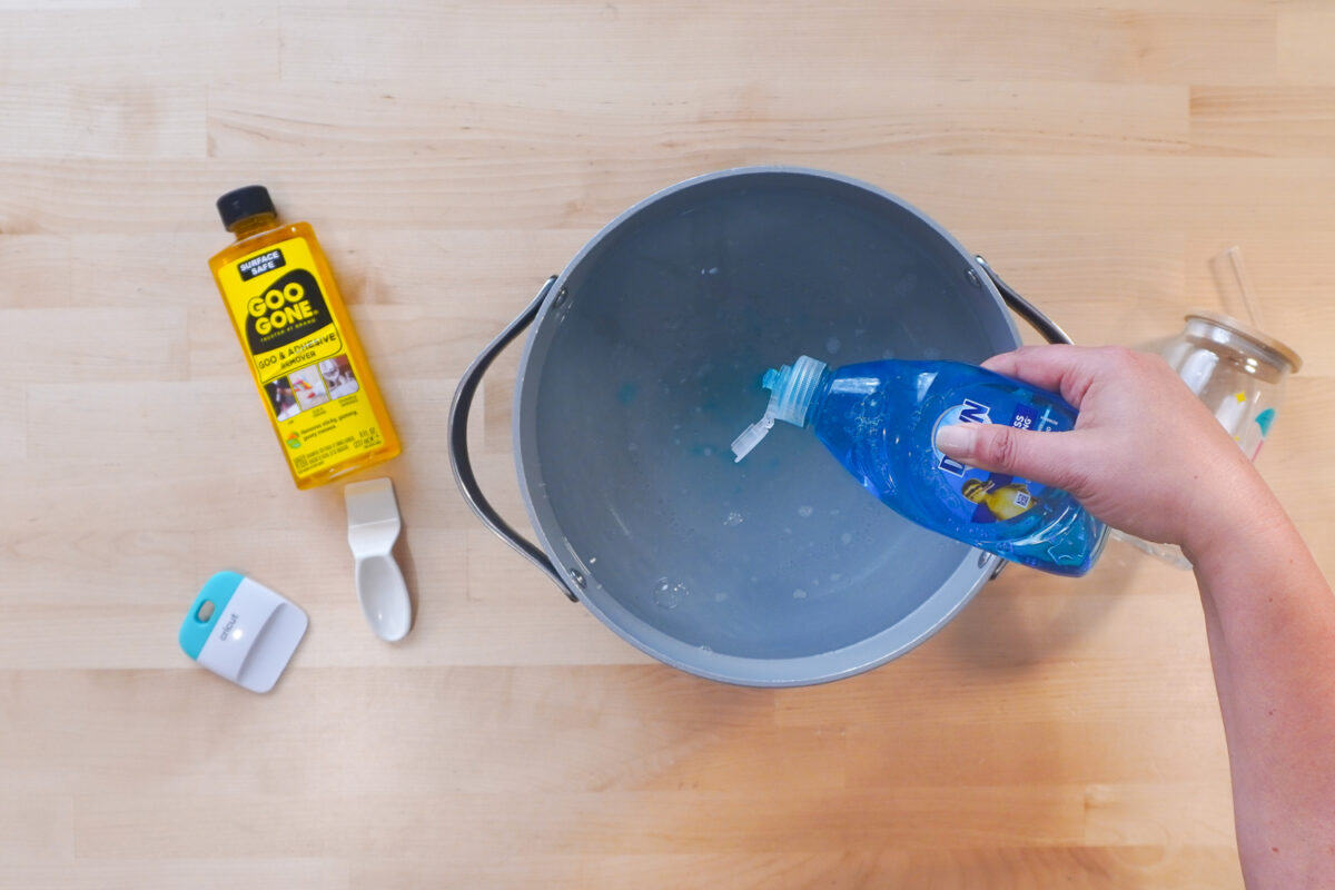 Hand adding some Dawn to a pot of hot water.