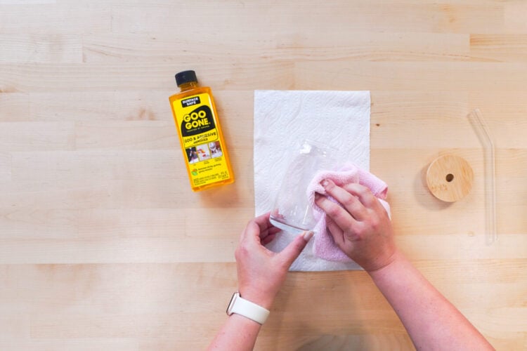 Hands rubbing Goo Gone onto a glass jar