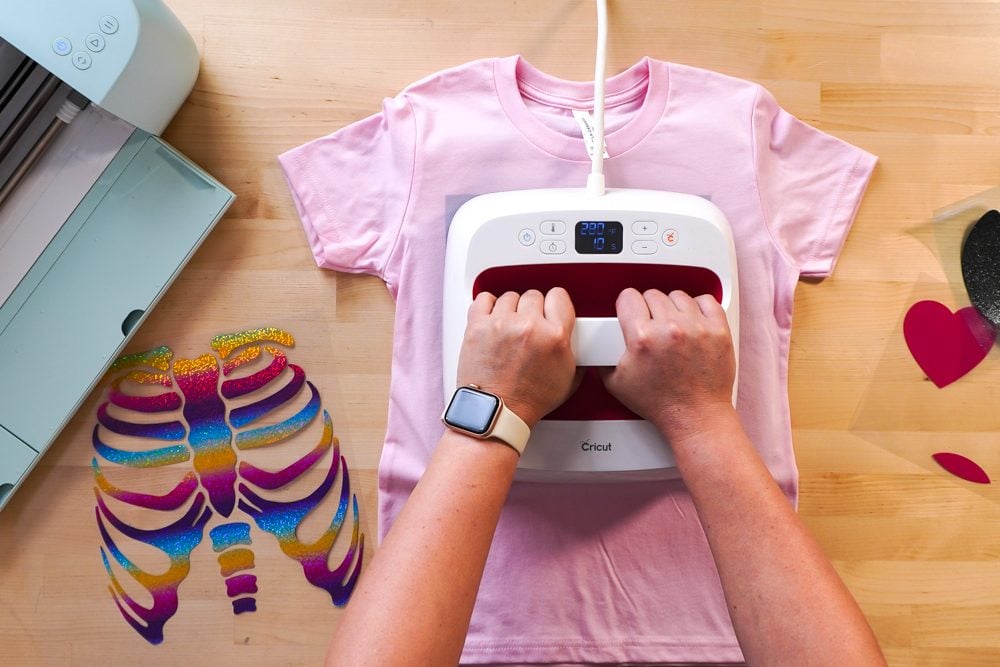 Hands pressing the pink t-shirt with an EasyPress