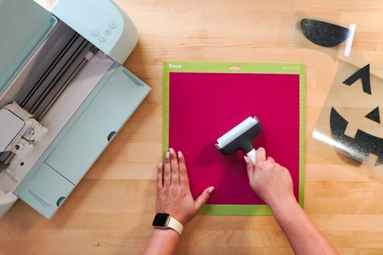 Hands using brayer on pink HTV