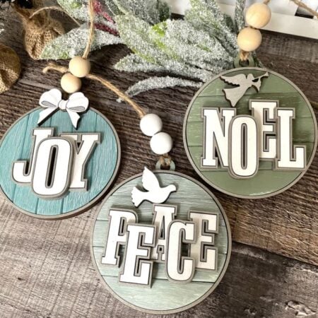 Wooden Christmas ornaments cut from wood with the words Joy, Noel and Peace on them