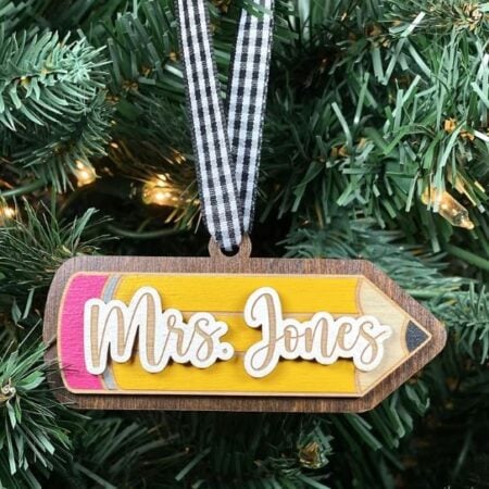 A Christmas ornament in the shape of a pencil and personalized with a teacher's name.