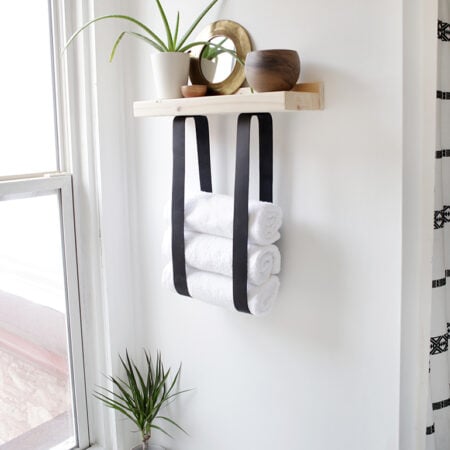 Image of a wooden and leather hanging shelf.