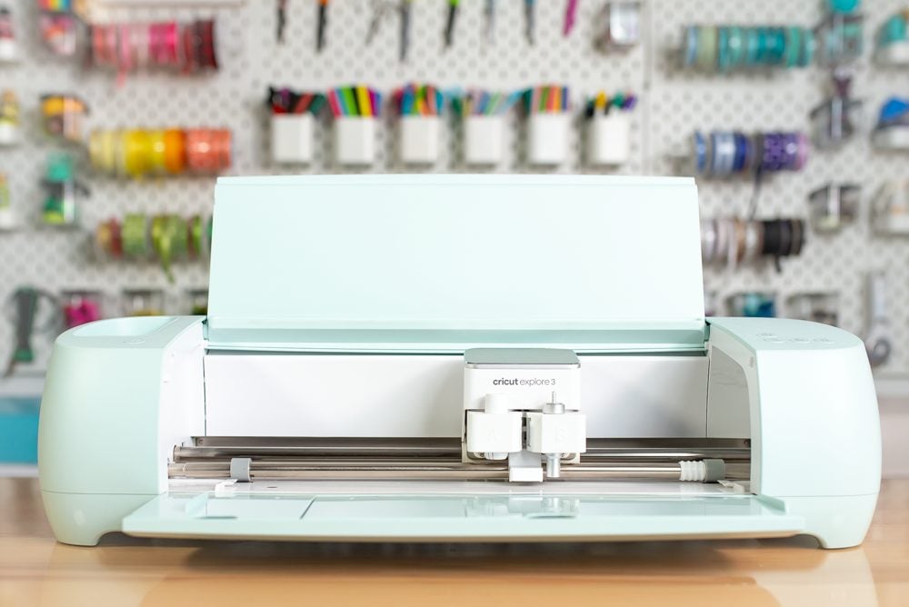 Cricut Explore 3 closed on a table with a peg board behind it.