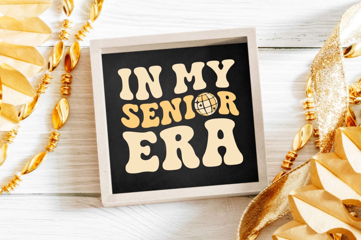 In My Senior Era SVG on a chalkboard sign with gold decorations