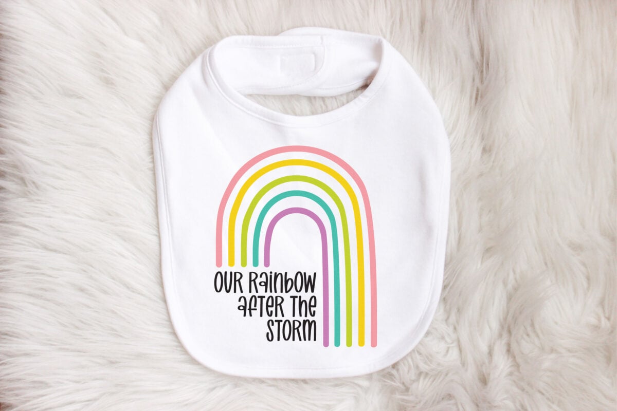 Our Rainbow After the Storm SVG on bib sitting on a faux fur