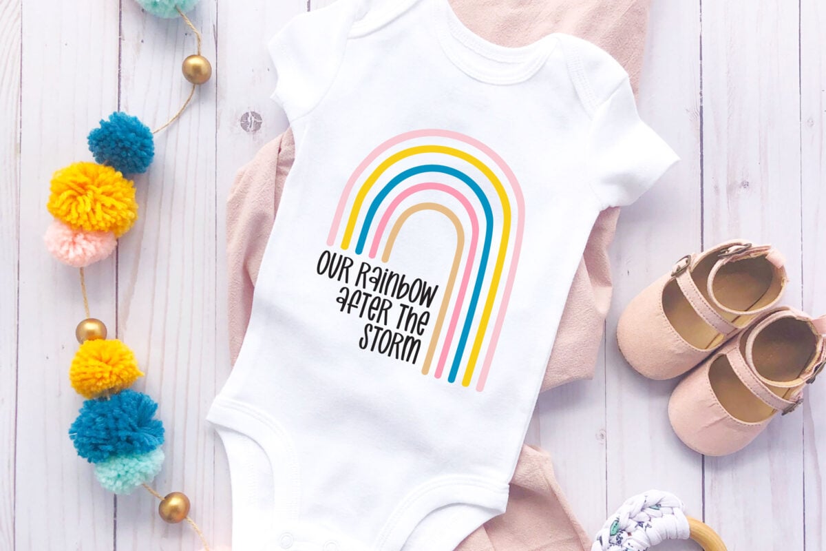 Our Rainbow After the Storm SVG on a onesie with baby accessories