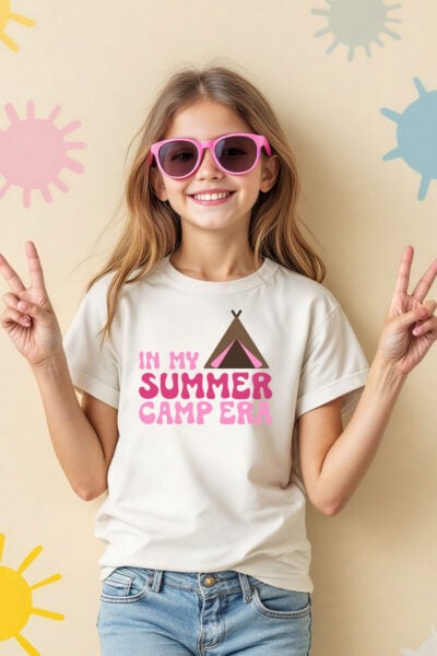 In My Summer Camp Era SVG on a girl's t-shirt. The girl is wearing sunglasses and giving peace signs.