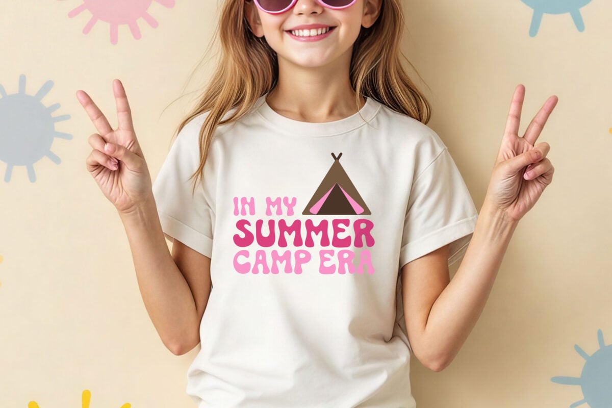 In My Summer Camp Era SVG on a girl's t-shirt. The girl is wearing sunglasses and giving peace signs.