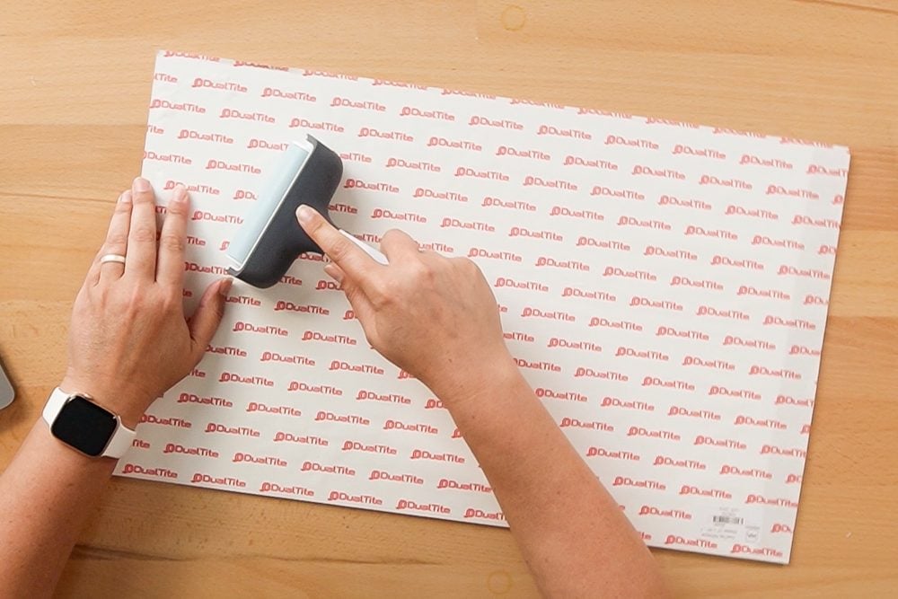 Hands using a brayer to smooth down the adhesive