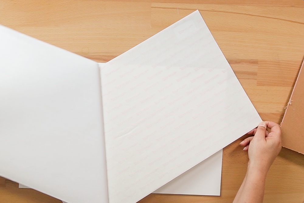 Hands peeling back the liner on the adhesive