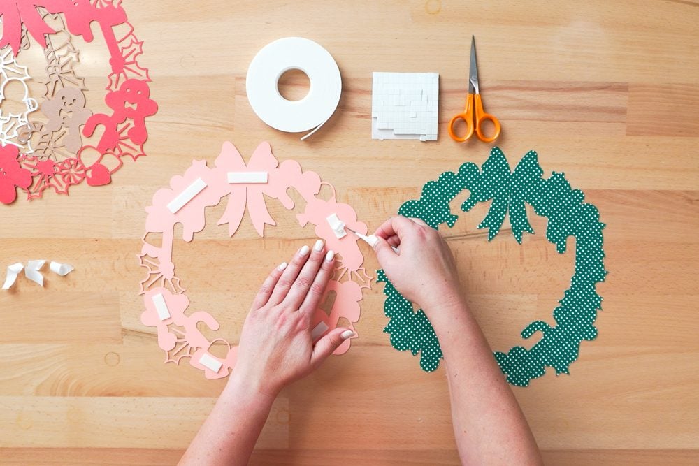Hands using tweezers to remove the backing from the foam strips on the pink layer