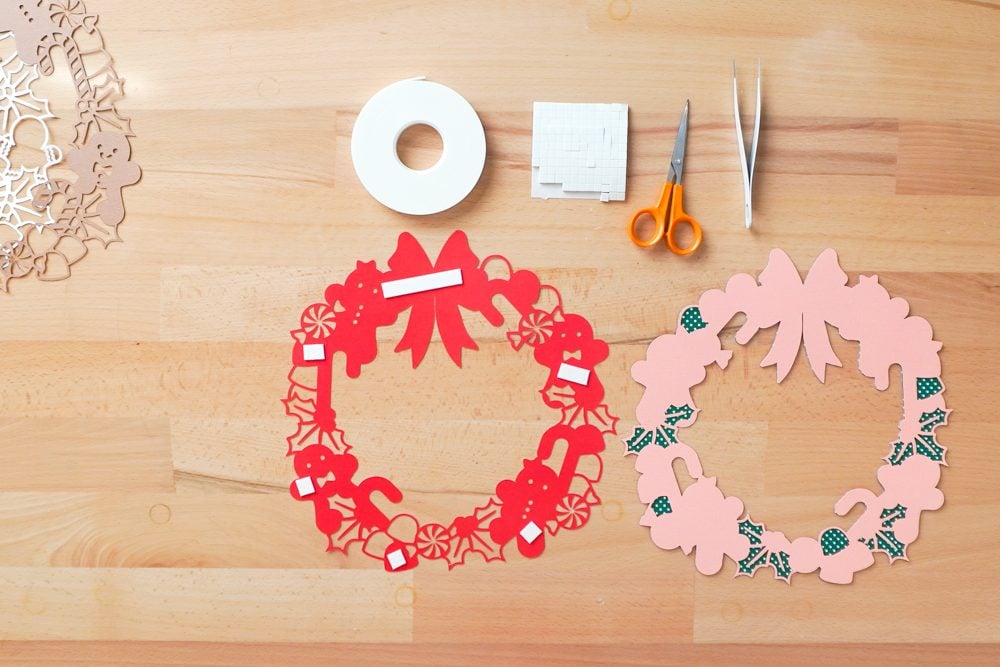 Hands applying foam strips to the back of the red cardstock layer