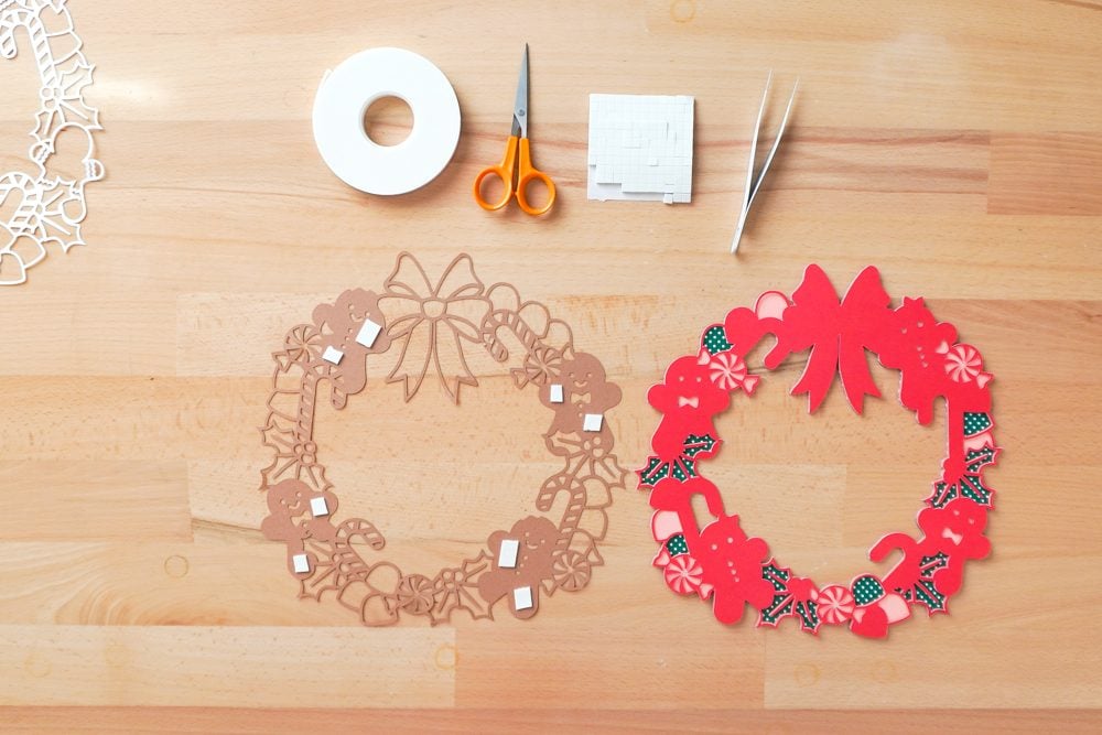 Hands applying foam strips to the back of the brown cardstock layer