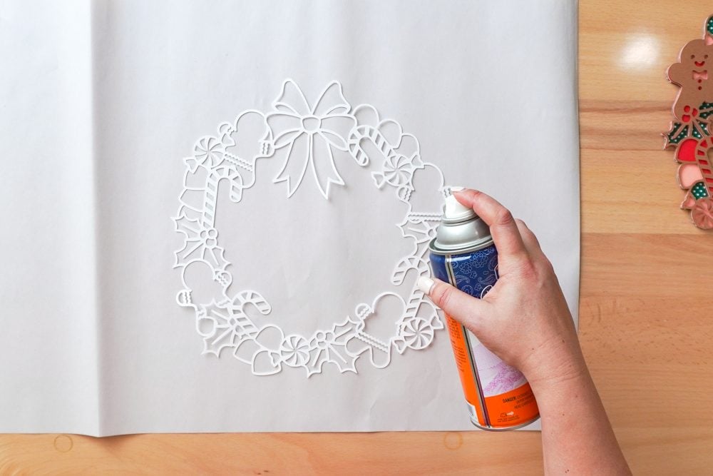 Hands using spray adhesive to coat the back of the white layer