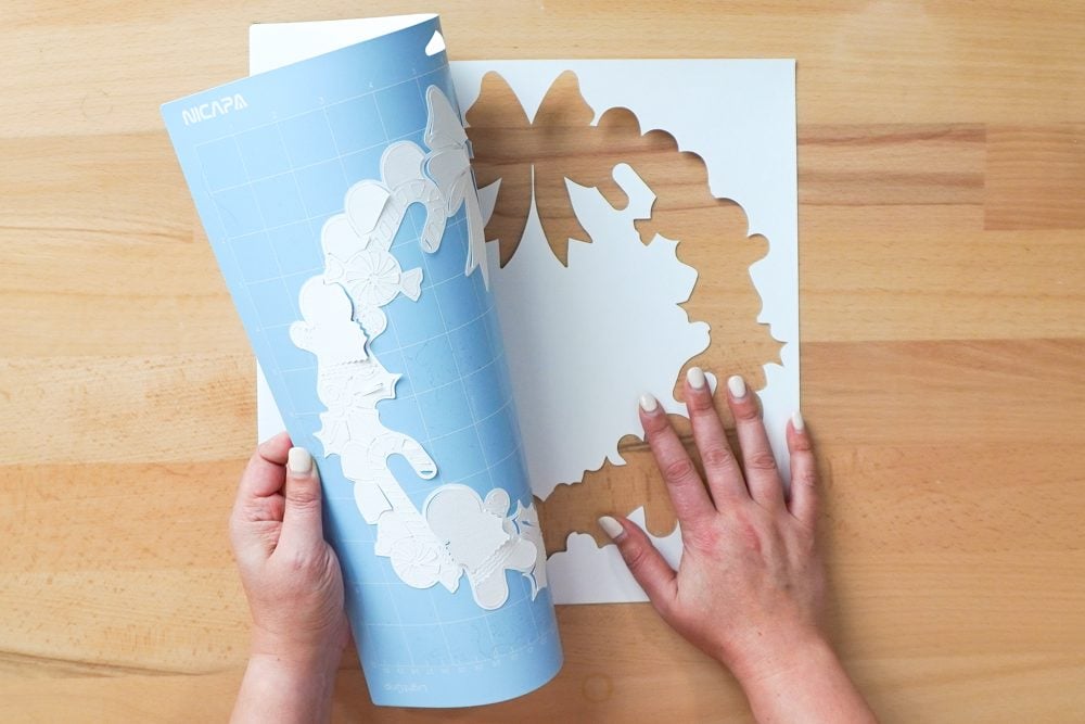 Hands removing the white layer from the mat by bending the mat away from the project