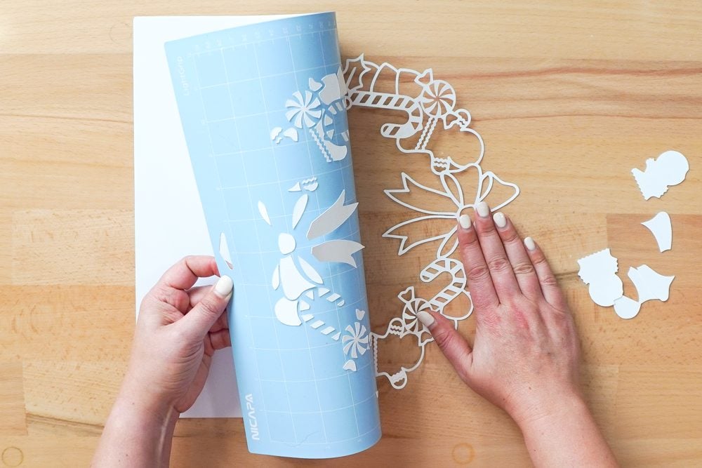 Hands removing the white layer from the mat by bending the mat away from the project