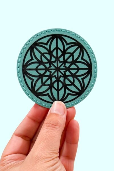 Hand holding an engraved leather coaster