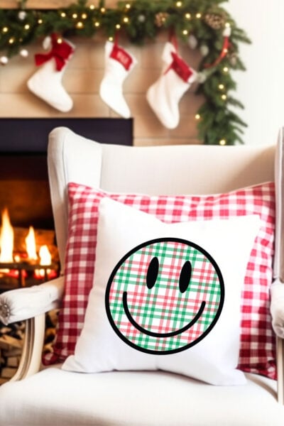 Christmas Happy Face sublimation file on a pillow on a chair surrounded by christmas decorations