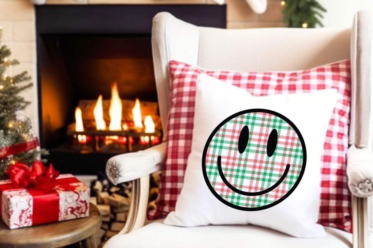Christmas Happy Face sublimation file on a pillow on a chair surrounded by christmas decorations